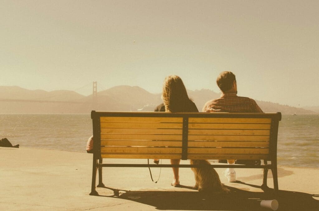 man and woman sitting on bench beside body of water. stress affects fertility and a relationship.