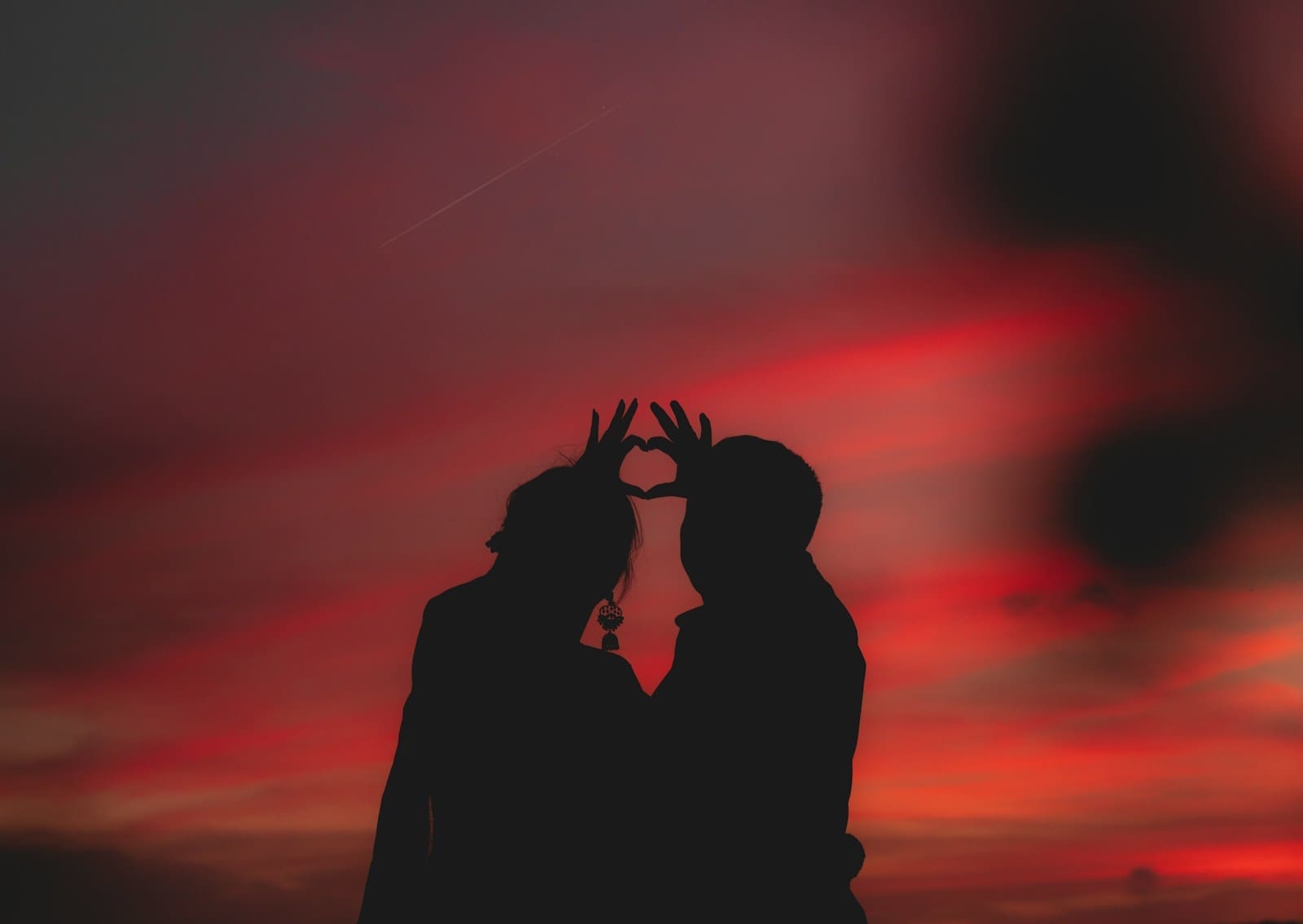 silhouette photography of two people making a heart shape with their hands. love and dating can be amazing at every age