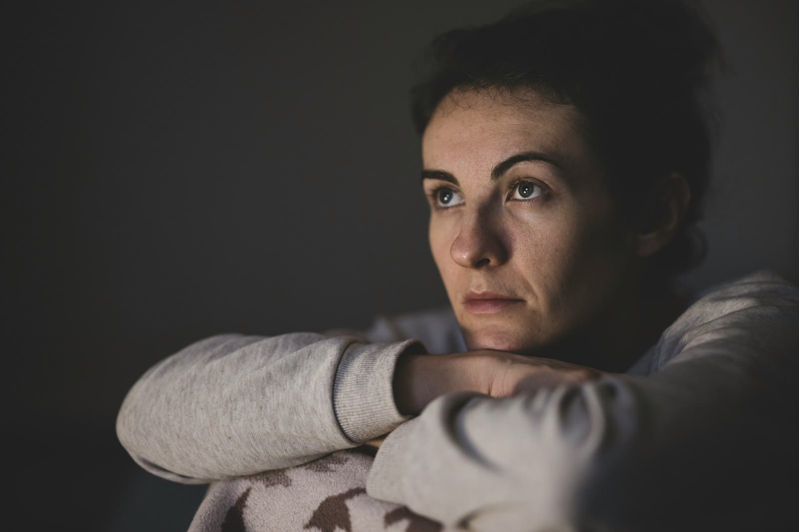 woman in gray long sleeve shirt, she rests her head on her folded arms