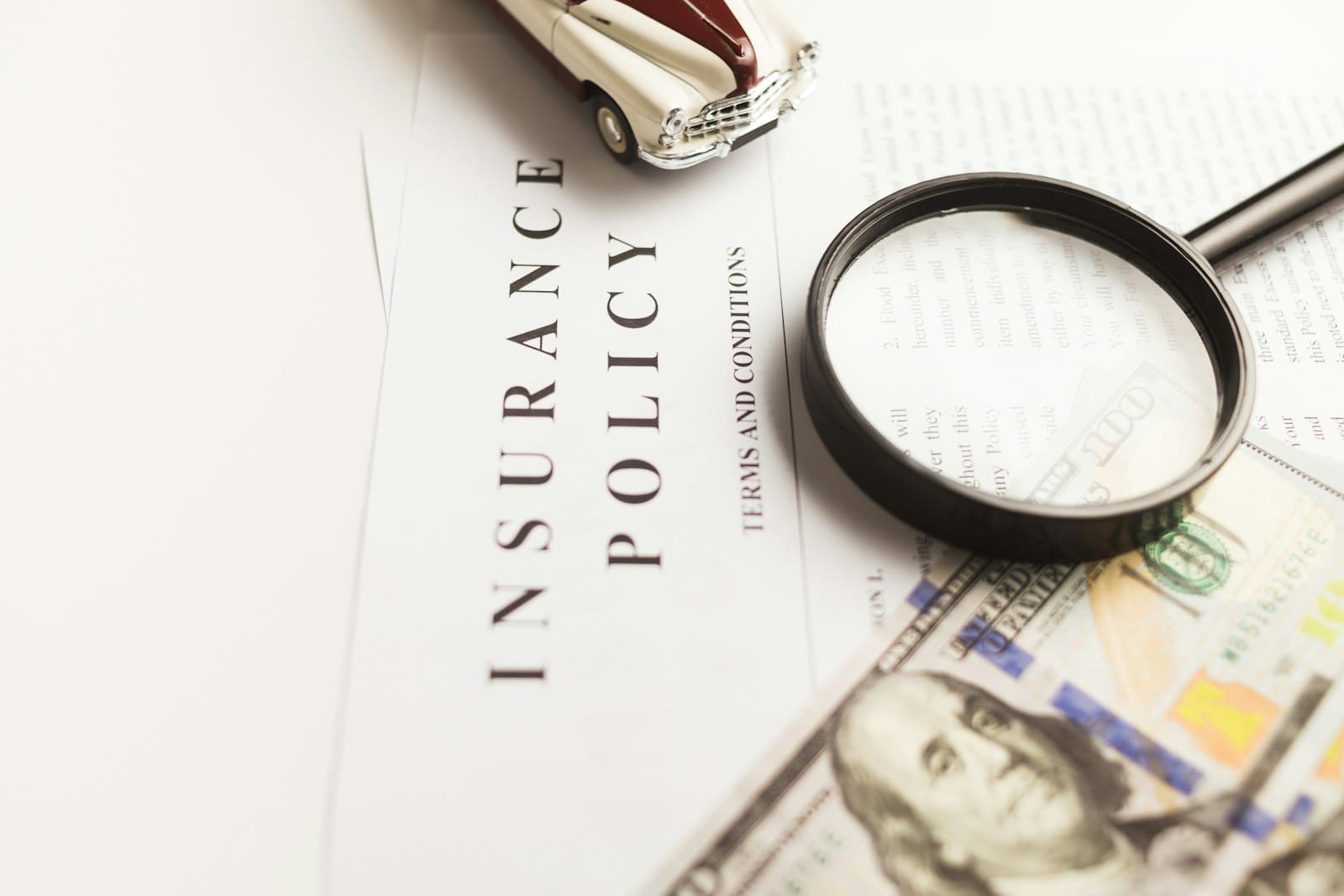 a magnifying glass sitting on top of a piece of paper that says Insurance Policy.
