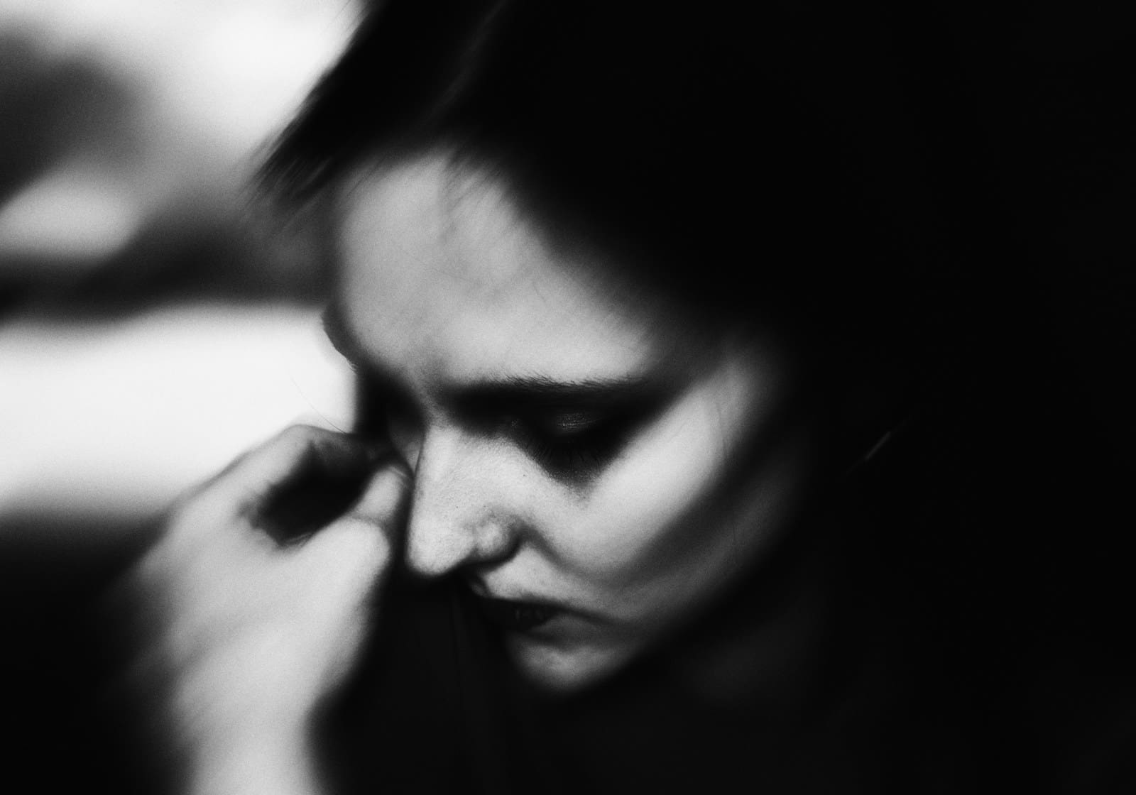 a black and white photo of a woman with her head bowed in grief.