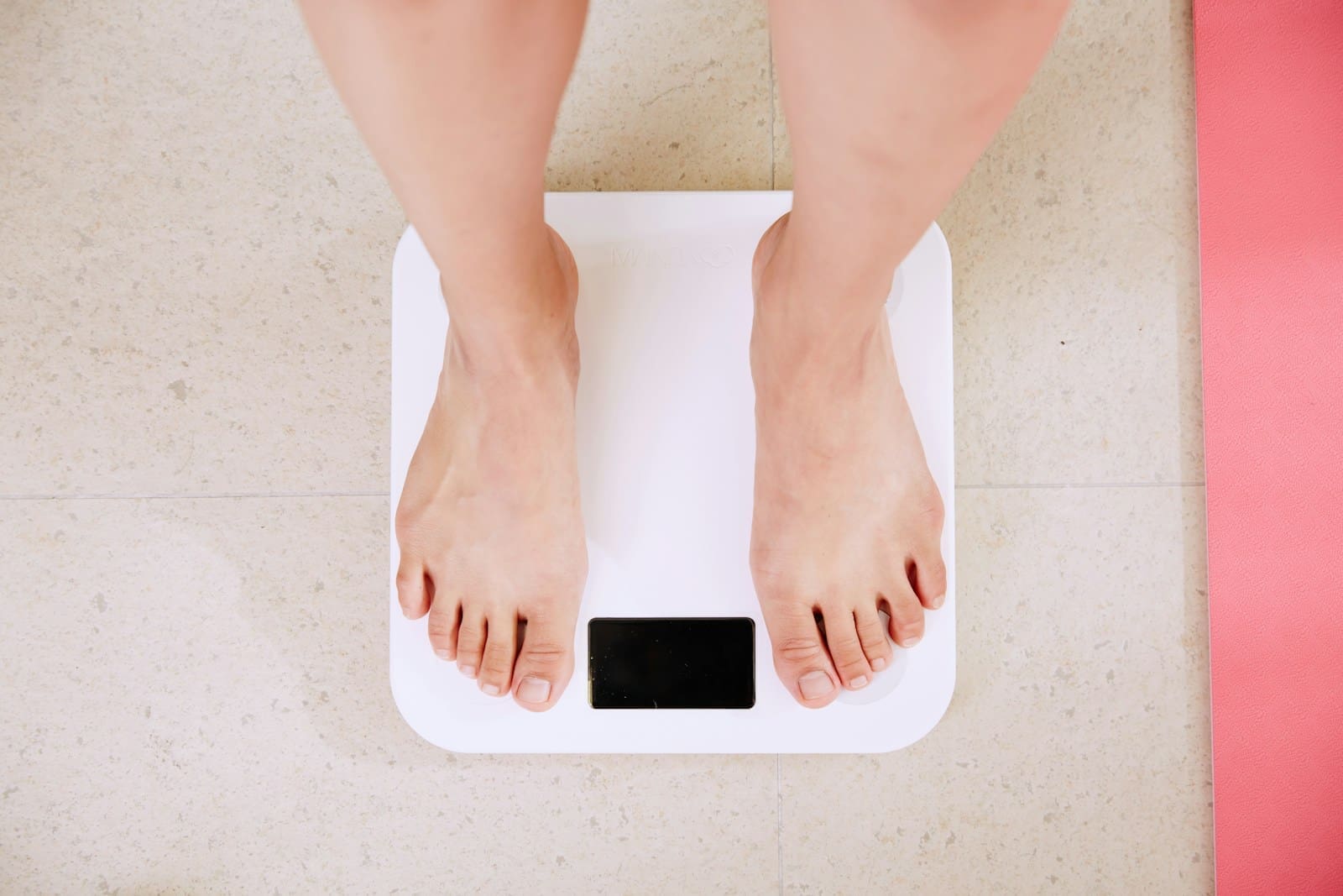 person standing on white digital bathroom scale, the view is from the calf of the leg down
