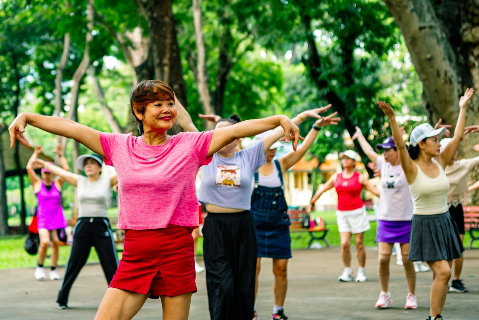 Group of women exercising together in a park. They are menopausal aged and vibrant in colorful clothes.