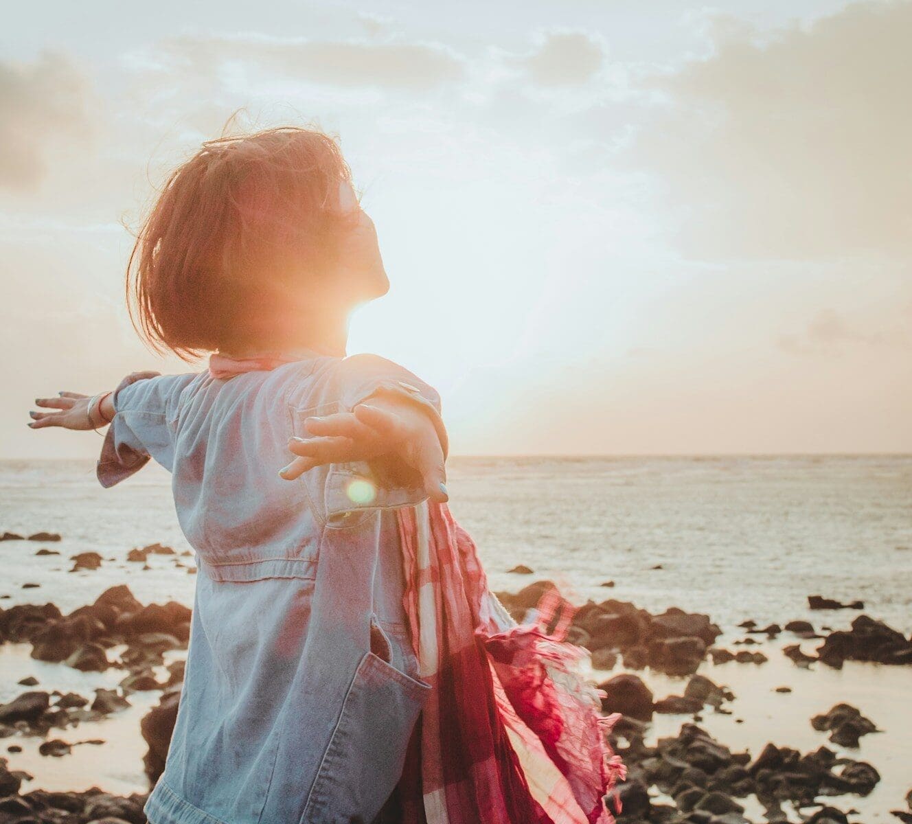 Photo by Fuu J woman spreading her arms wide as the sun rises