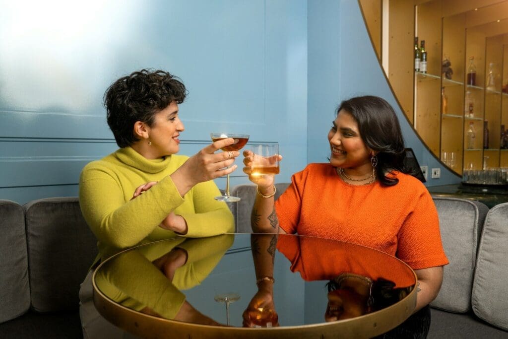 a couple of women sitting at a table toasting to friendshio. Our social connections keep us healthy